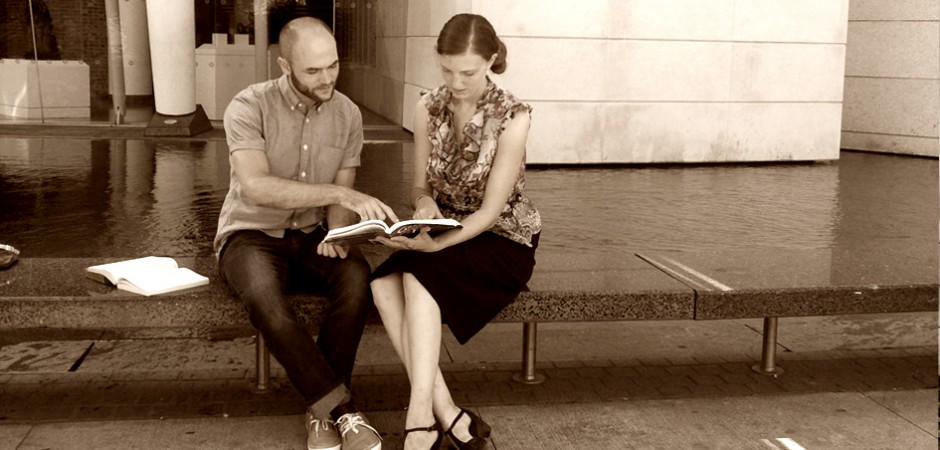 Young man patiently teaching a young woman French during a lesson in a serene modern setting
