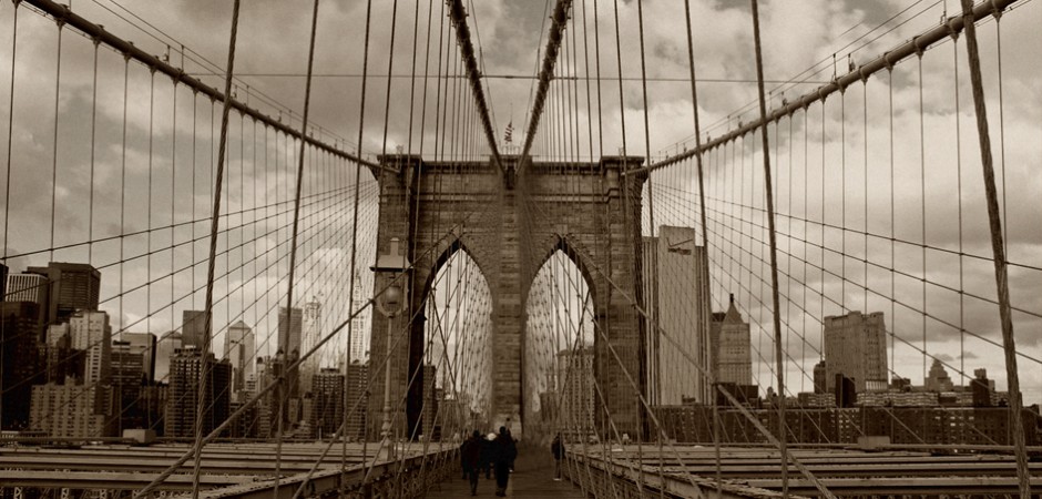 a wide-angle shot of the Brooklyn Bridge, empty and calm on a cloudy day, in a vintage sepia tone