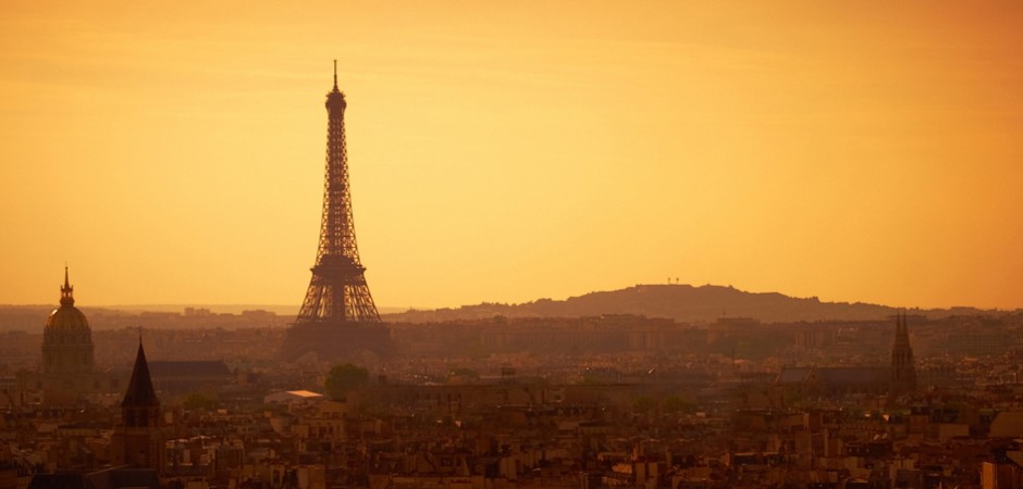 A romantic, golden and hazy Paris panoramic view at sunset featuring the Eiffel Tower and the Sacré Coeur.